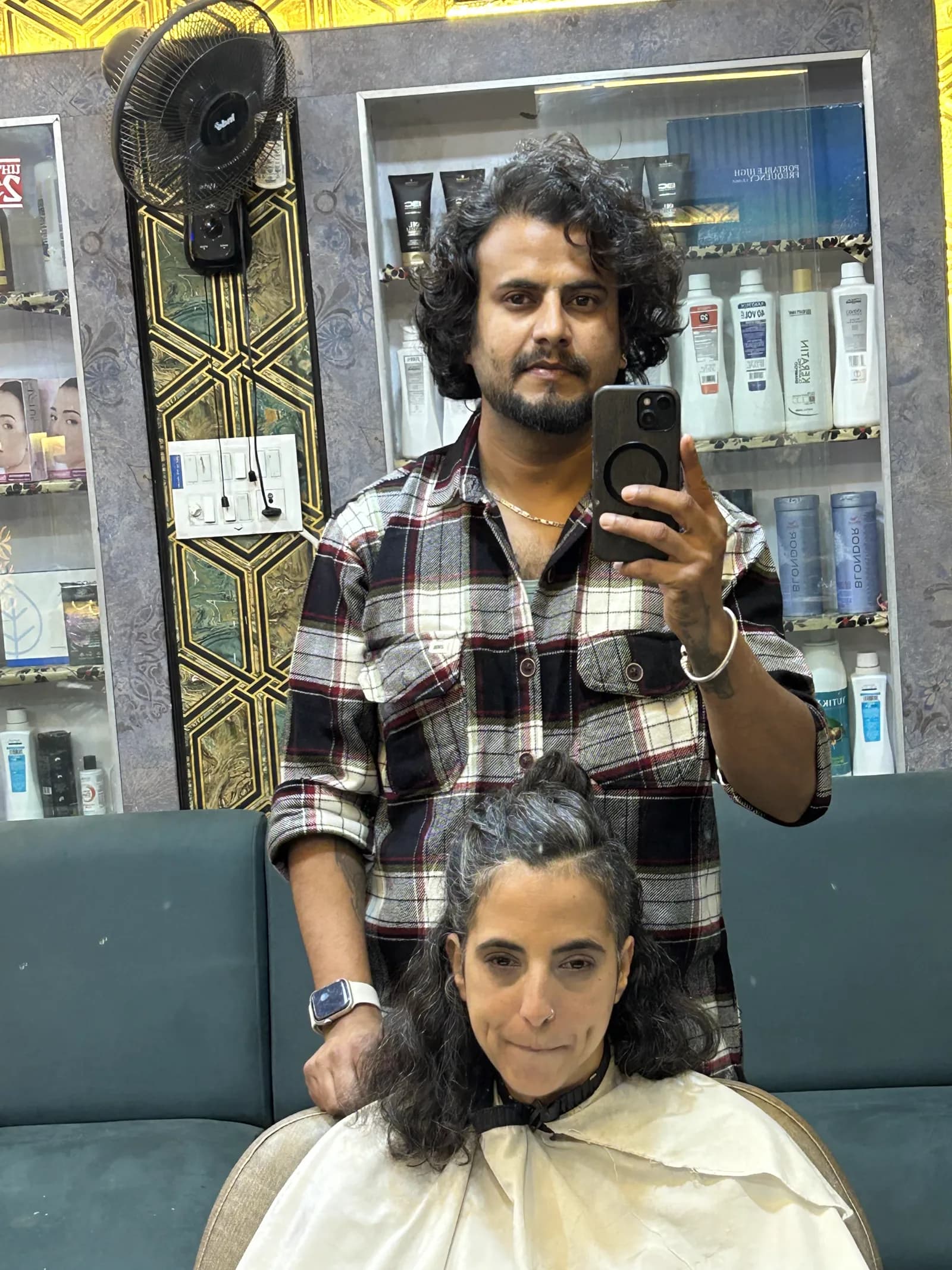 A guest and stylist reflected in the salon mirror